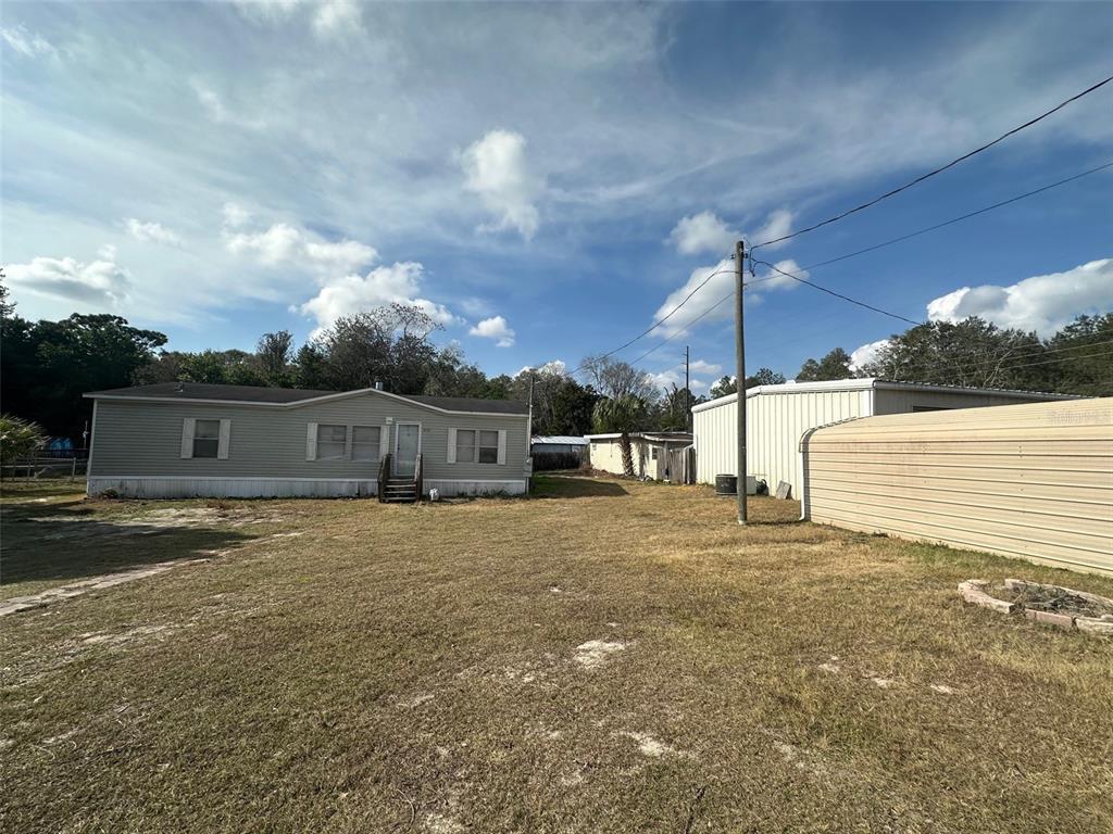 A manufactured home sits on a large, grassy lot next to a metal storage building — 7160 NE 7TH STREET, OCALA, FL