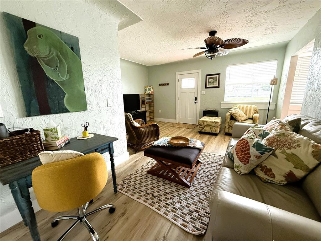 A living room features a desk, a sofa, a ceiling fan, and light wood flooring — 421 VIRGINIA AVENUE, MADEIRA BEACH, FL