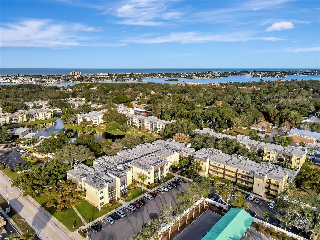 An aerial view shows multi-story apartment buildings surrounded by trees, parking lots, and a waterway — 14130 ROSEMARY LANE UNIT 1318, LARGO, FL