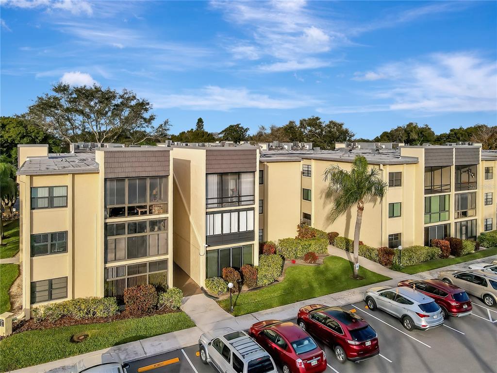 An exterior view of a multi-story apartment building with a parking lot in the foreground — 14130 ROSEMARY LANE UNIT 1318, LARGO, FL
