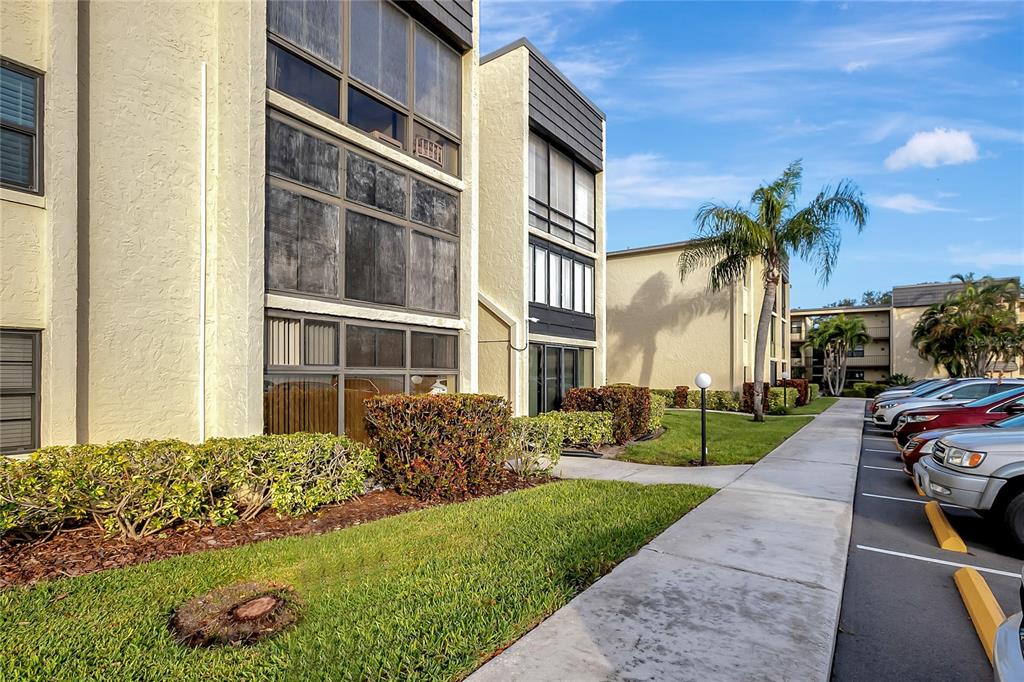 An exterior view of a multi-story apartment building with a sidewalk and parking lot — 14130 ROSEMARY LANE UNIT 1318, LARGO, FL