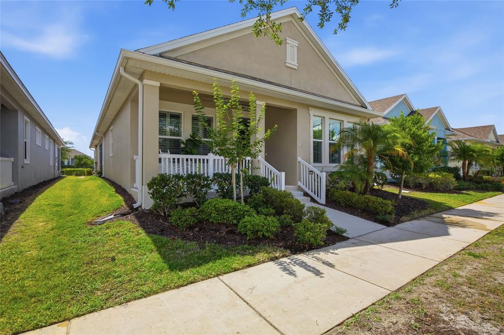 A tan single-story house with a white front porch and a sidewalk in the foreground — 725 WINTERSIDE DRIVE, APOLLO BEACH, FL