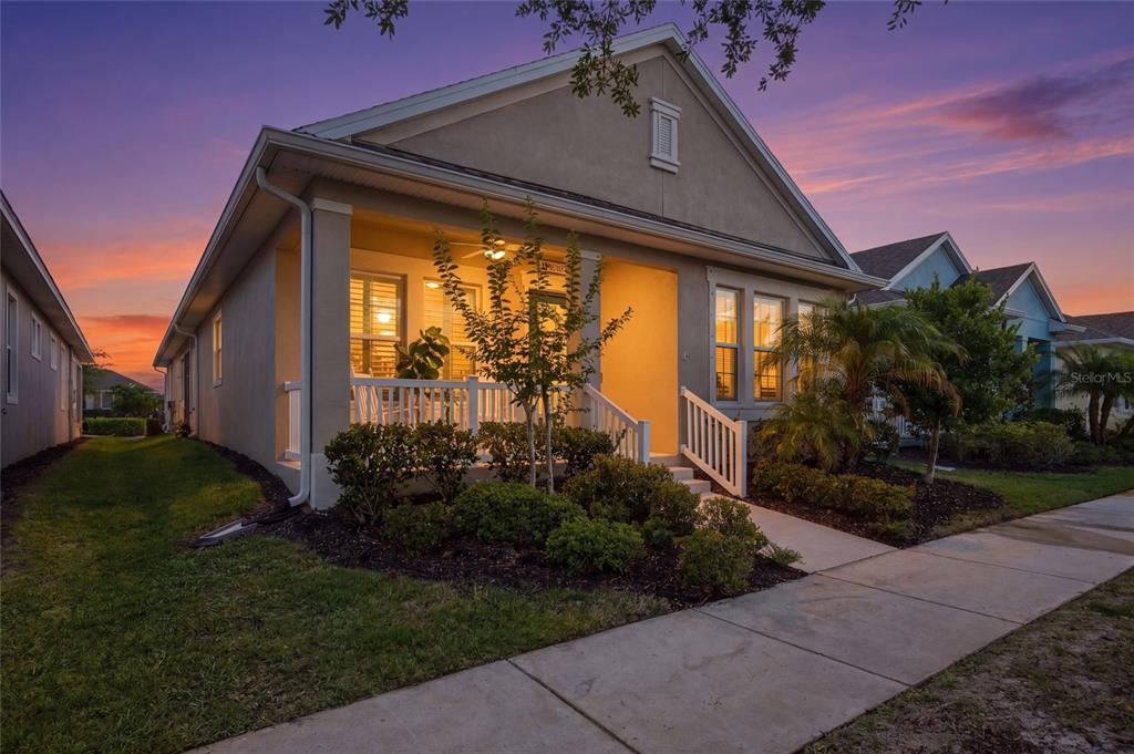 A single-story house with a front porch, white railings, and landscaping at sunset — 725 WINTERSIDE DRIVE, APOLLO BEACH, FL