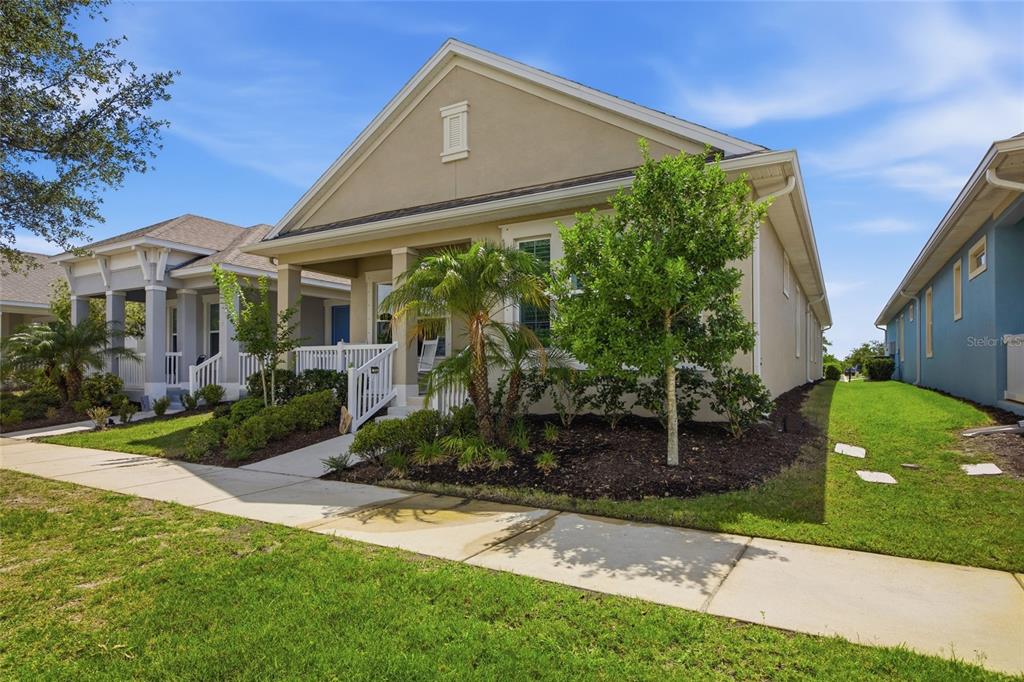 A tan single-story house with a front porch, palm tree, and landscaping under a blue sky — 725 WINTERSIDE DRIVE, APOLLO BEACH, FL
