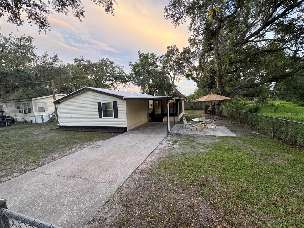 A single-story house with light siding, a concrete driveway, and a patio with an umbrella — 8801 MARC DAVID, GIBSONTON, FL