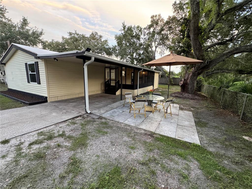 A house exterior features a concrete patio, a dining set with an umbrella, and siding — 8801 MARC DAVID, GIBSONTON, FL