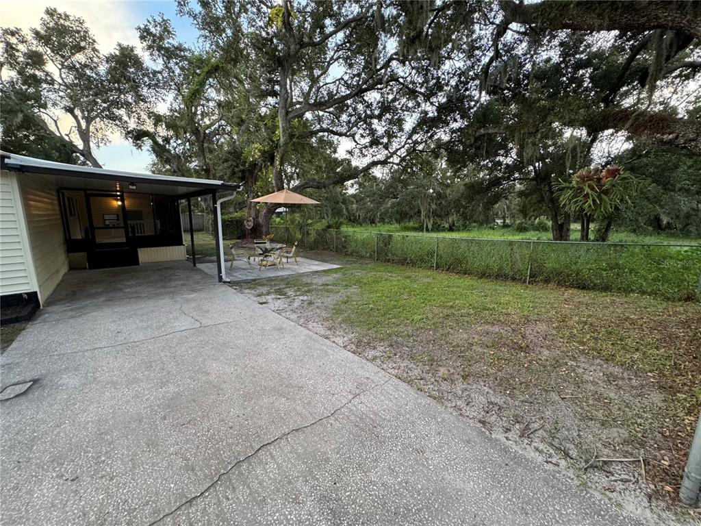 A concrete driveway leads to a screened porch and a patio area with an umbrella — 8801 MARC DAVID, GIBSONTON, FL