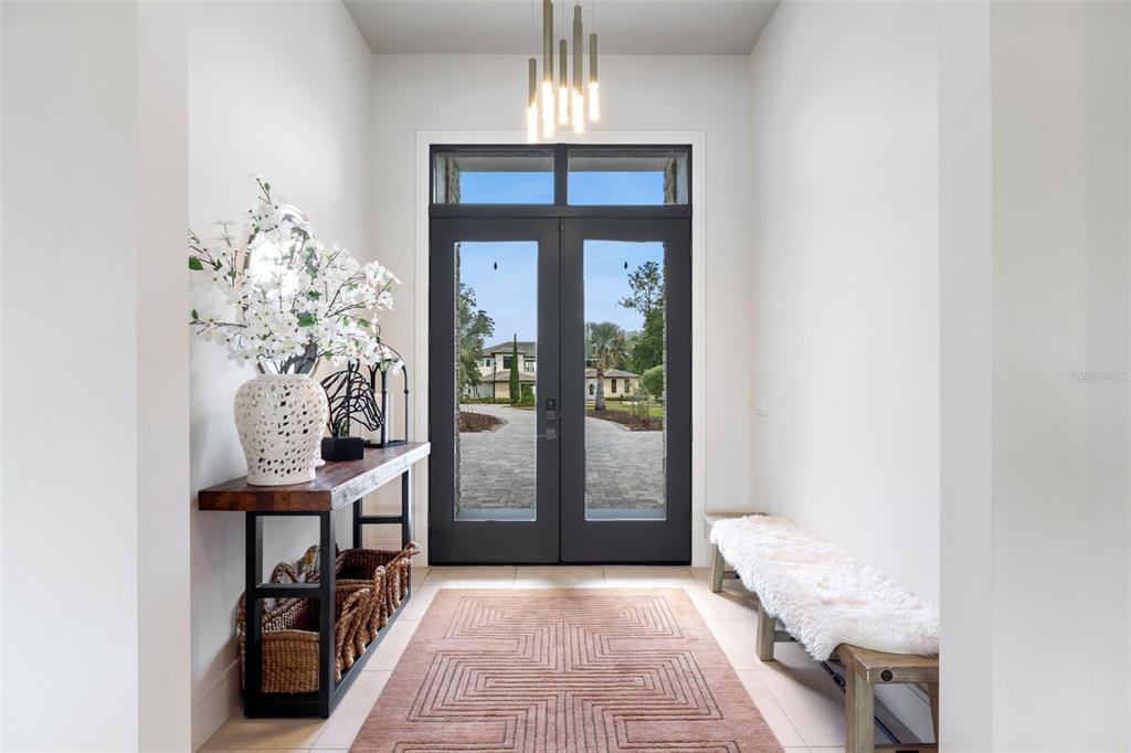 An entryway features a double glass door, a wooden console table, and a bench — 15220 PENDIO DRIVE, BELLA COLLINA, FL