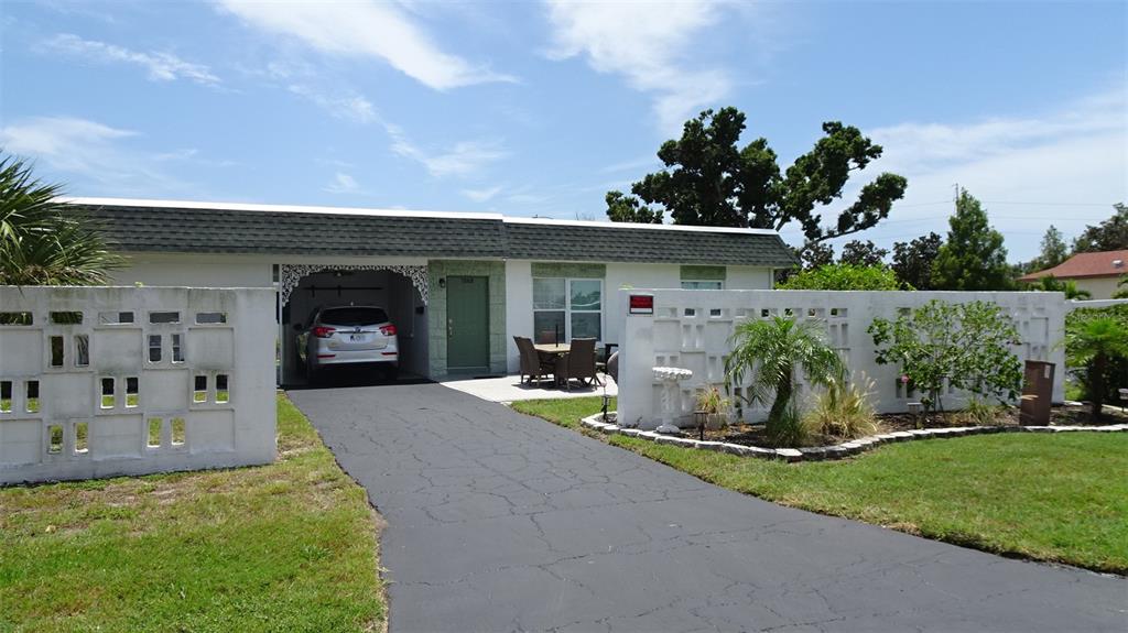 A patio with a dining set and chairs sits outside a house with stone accents — 7868 40TH AVENUE N UNIT 7868, ST PETERSBURG, FL