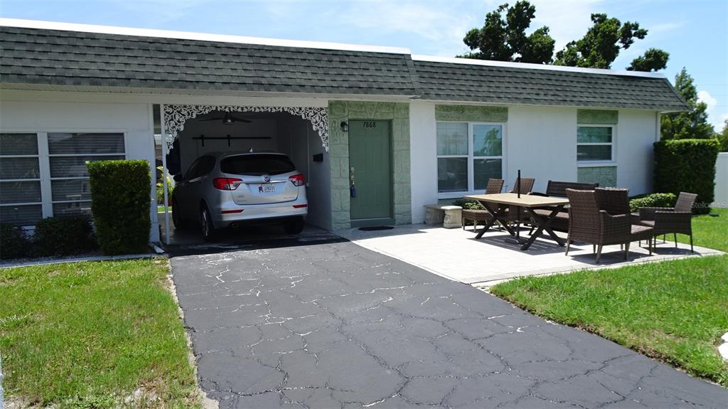 A single-story house with a white decorative privacy wall, a paved driveway, and landscaping — 7868 40TH AVENUE N UNIT 7868, ST PETERSBURG, FL