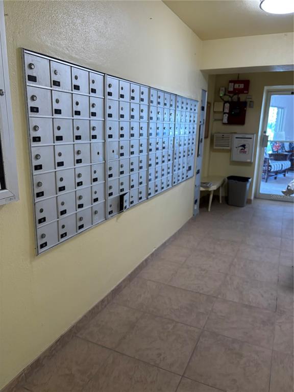 A hallway features a large wall-mounted metal mailbox unit and tile flooring — 4725 COVE CIRCLE UNIT 104, MADEIRA BEACH, FL