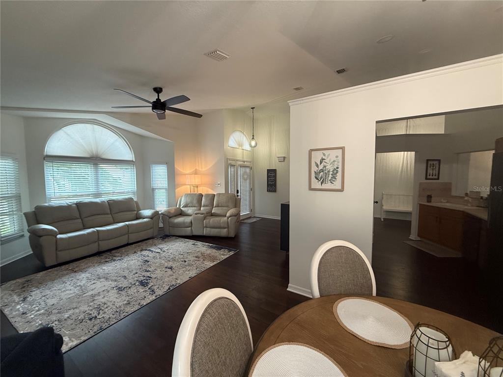 A living room with dark wood floors, a large area rug, and white leather furniture — 6060 CONDOR DRIVE, LAKELAND, FL