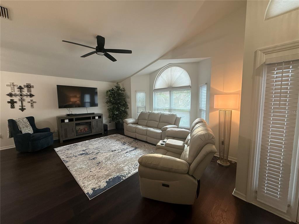 A living room features dark wood floors, a light-colored sofa set, and a ceiling fan — 6060 CONDOR DRIVE, LAKELAND, FL