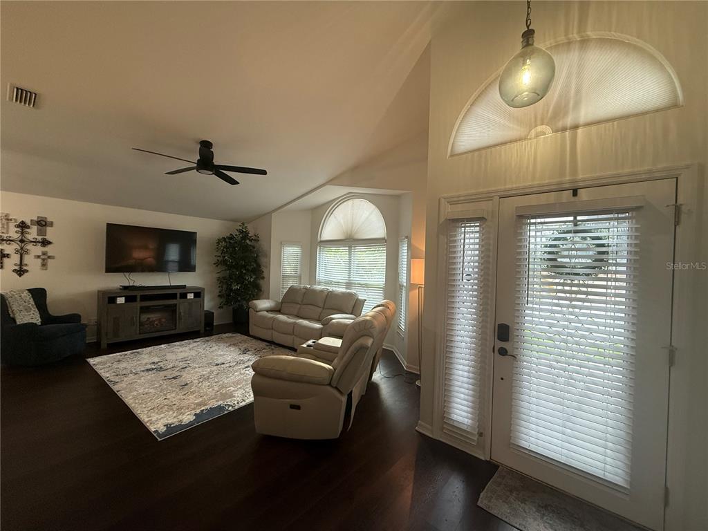 A living room features dark wood floors, a vaulted ceiling, and a glass-paneled front door — 6060 CONDOR DRIVE, LAKELAND, FL