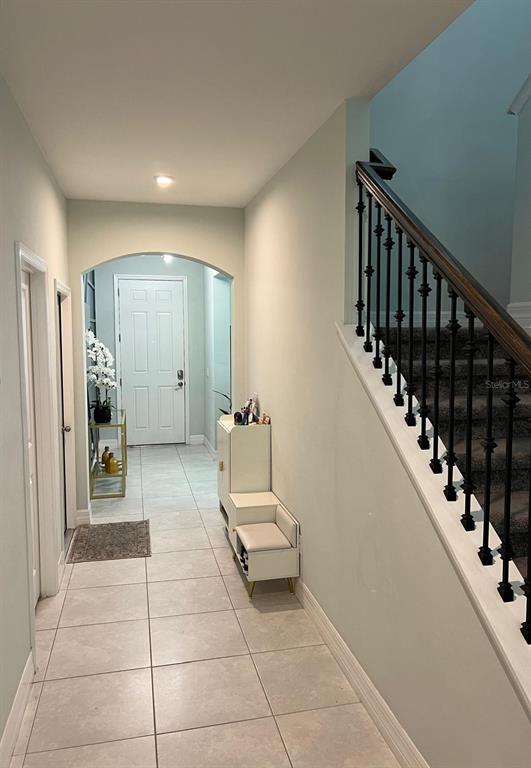 An entryway features light tile floors, an arched doorway, and a staircase with iron railings — 1506 PINES END PLACE, ST CLOUD, FL