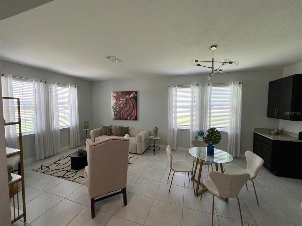 A living and dining area features tile flooring, neutral walls, and a modern light fixture — 1506 PINES END PLACE, ST CLOUD, FL