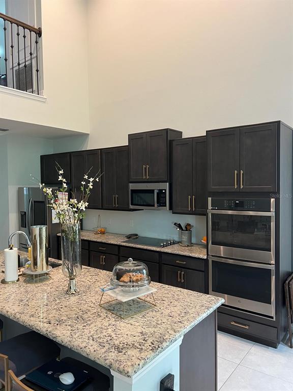 A kitchen features dark wood cabinets, granite countertops, stainless steel appliances, and a large island — 1506 PINES END PLACE, ST CLOUD, FL