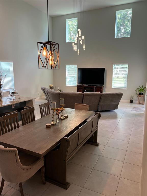 An open-concept dining and living area features a wooden table, sectional sofa, and high ceilings — 1506 PINES END PLACE, ST CLOUD, FL