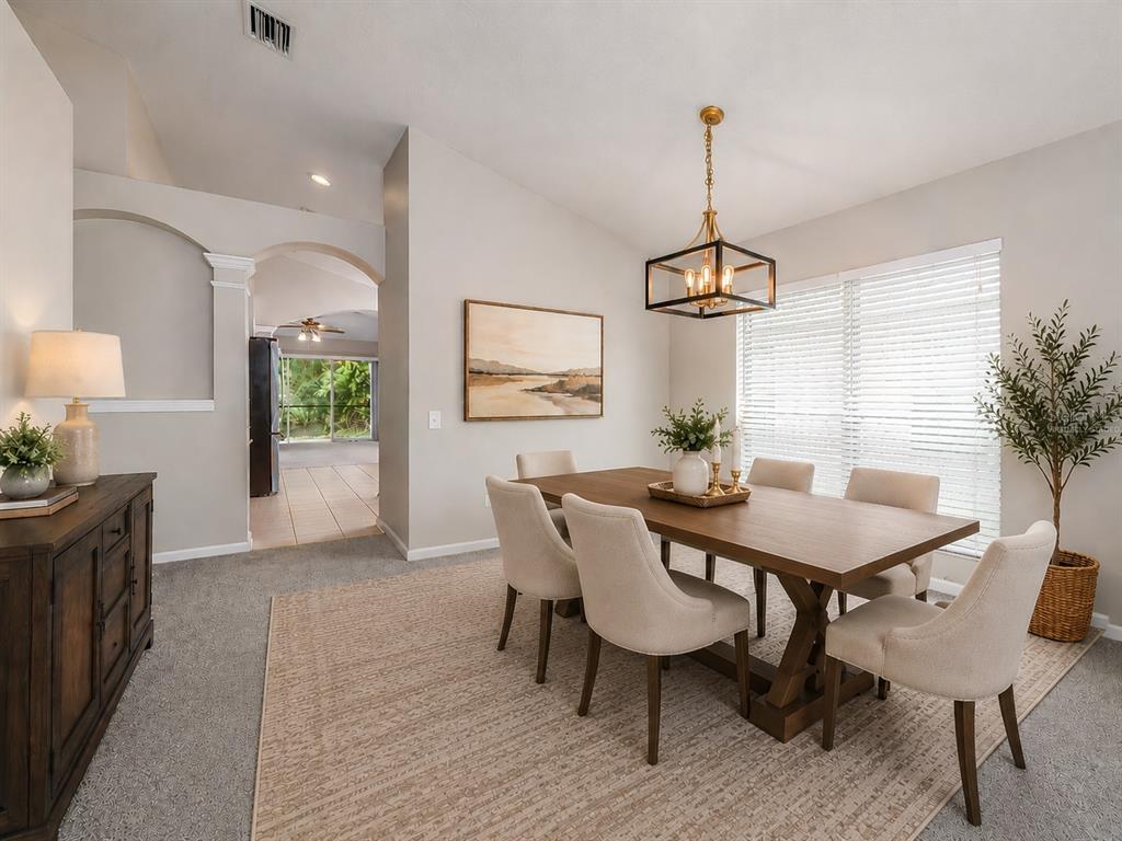 A dining room with a wooden table, six upholstered chairs, a chandelier, and a rug — 25342 LEXINGTON OAKS BOULEVARD, WESLEY CHAPEL, FL