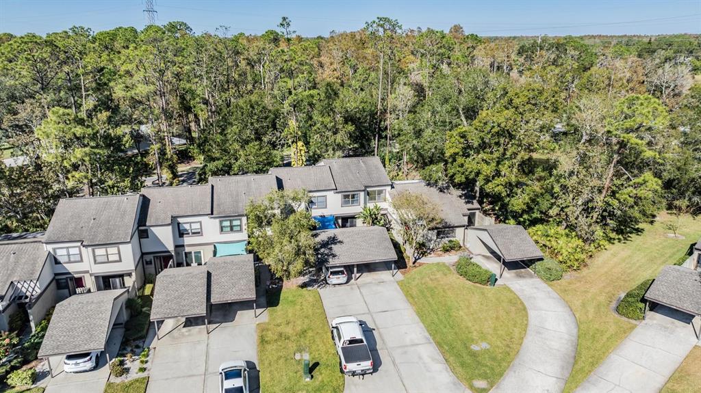 An aerial view shows a multi-unit townhouse complex with attached carports and paved driveways — 215 WOODS LANDING TRAIL, OLDSMAR, FL