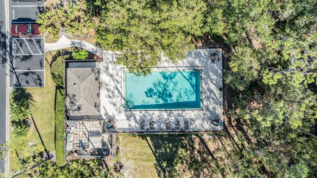 An aerial view shows a rectangular swimming pool, a covered patio, and adjacent parking spaces — 215 WOODS LANDING TRAIL, OLDSMAR, FL