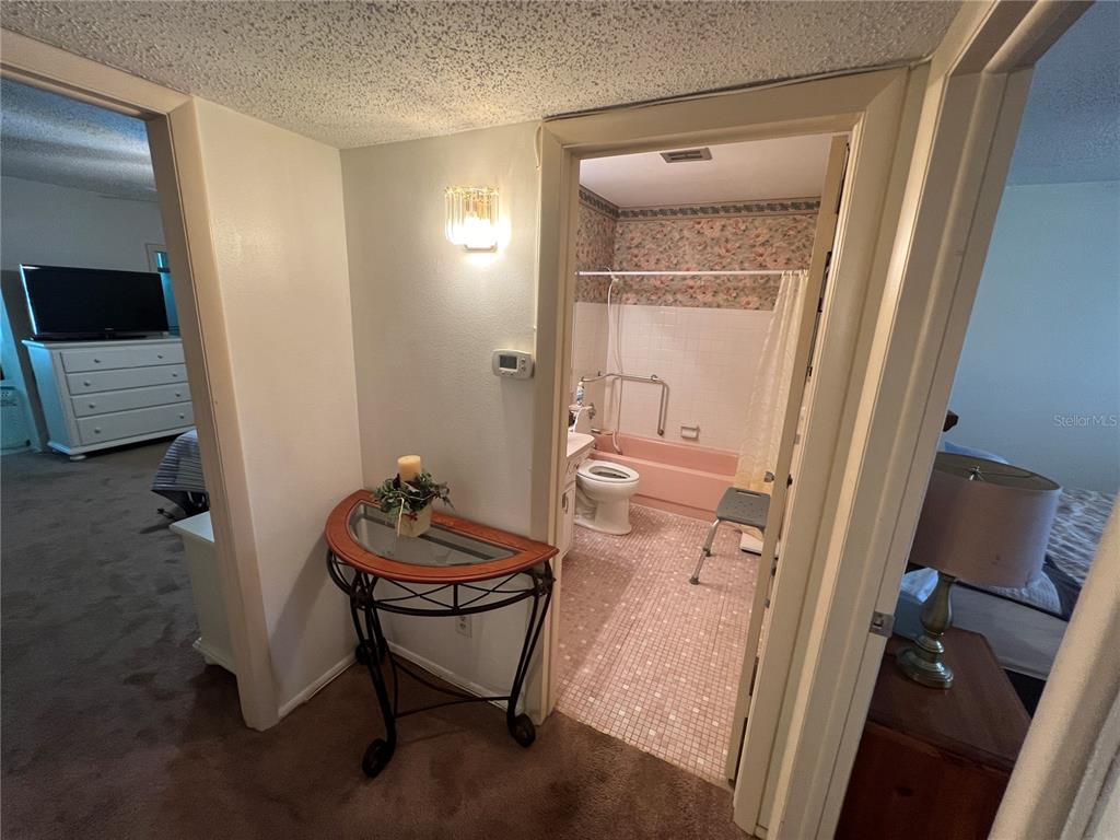 A hallway leads to a bathroom with a pink tub and floral wallpaper — 2361 ECUADORIAN WAY UNIT 33, CLEARWATER, FL