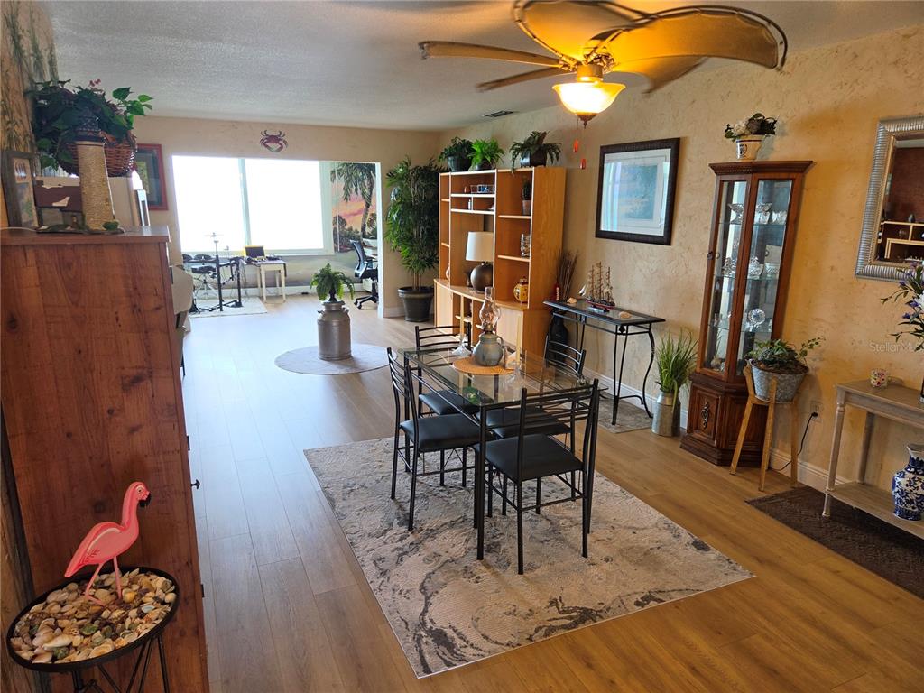 A dining area with a glass table and chairs sits in an open-concept living space — 7 DUNOON PLACE UNIT 309, DUNEDIN, FL