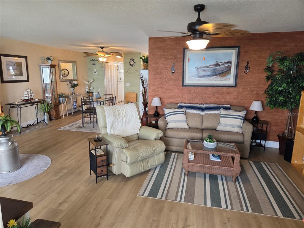 A living room features a beige sofa, a recliner, and a dining area in the background — 7 DUNOON PLACE UNIT 309, DUNEDIN, FL