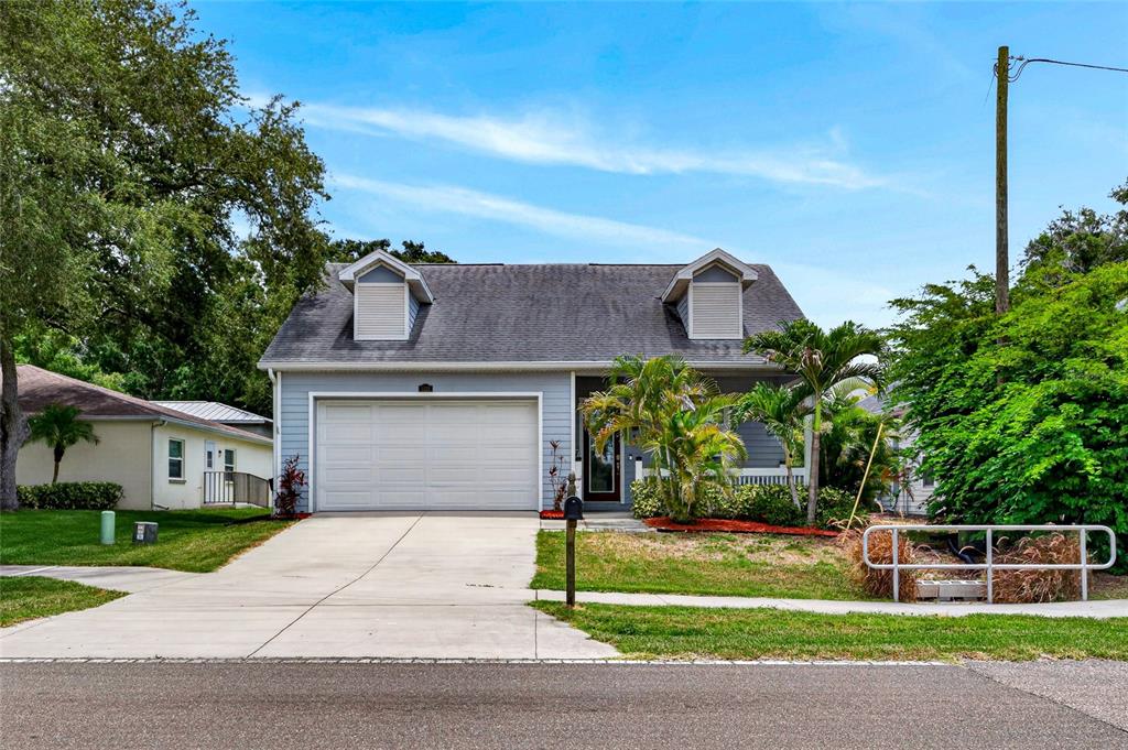 A two-story house with a light blue exterior, a two-car garage, and two dormer windows — 1535 PINEHURST ROAD, DUNEDIN, FL