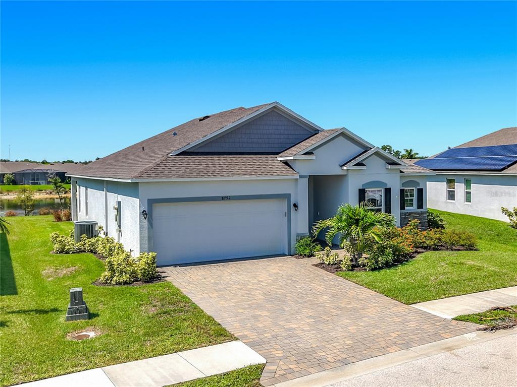 A single-story house with a paved driveway, two-car garage, and a landscaped front yard — 8792 CASCADE PRICE CIRCLE, NORTH FORT MYERS, FL