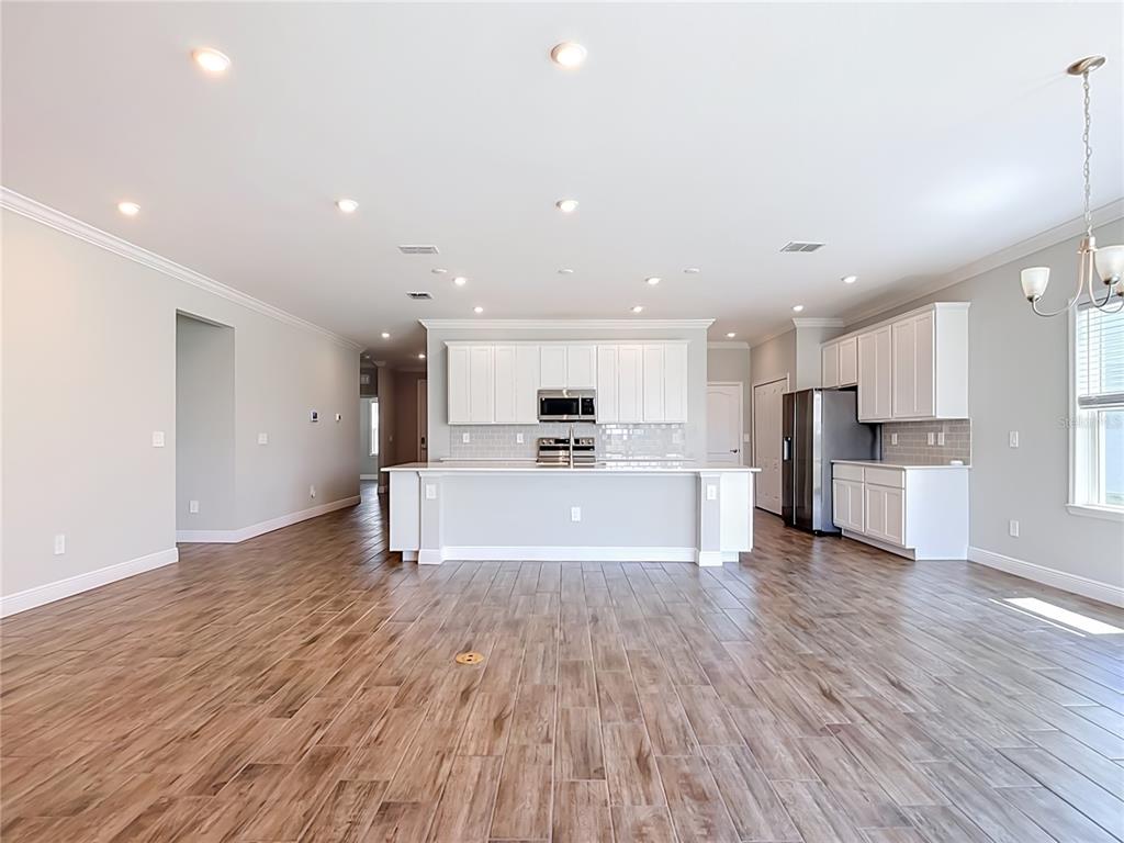 A kitchen with white cabinets, a central island, and wood-look tile flooring — 8792 CASCADE PRICE CIRCLE, NORTH FORT MYERS, FL