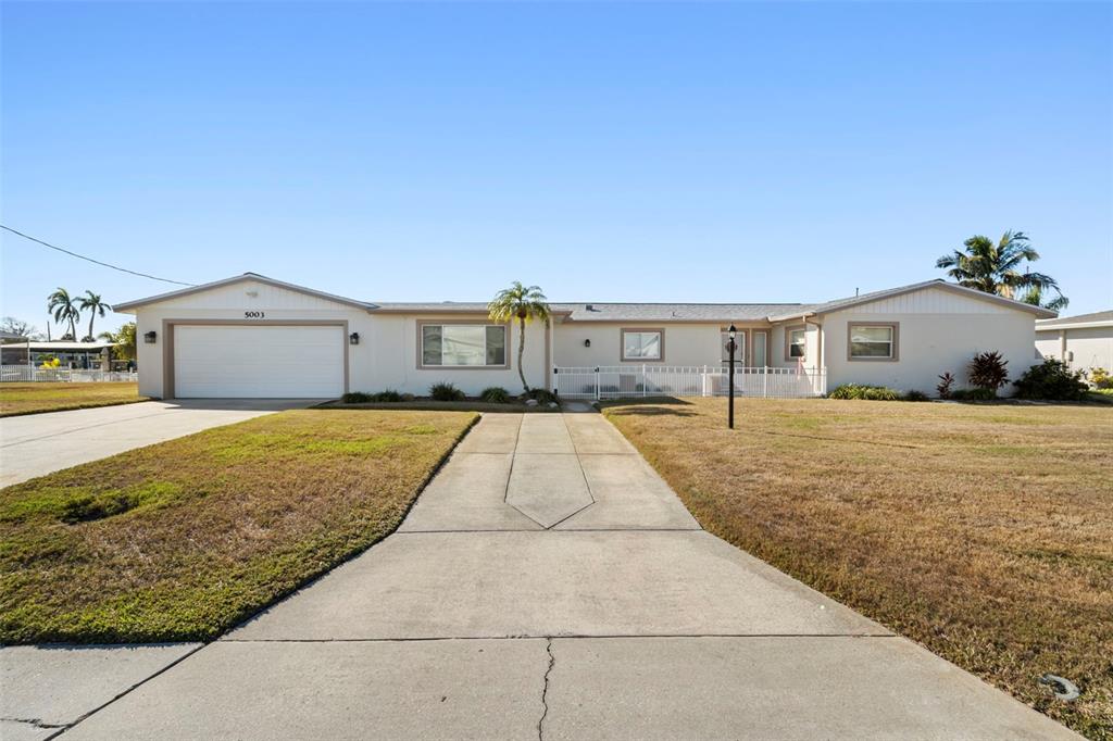 A single-story house with a white exterior, a two-car garage, and a concrete driveway — 5003 COMMONWEALTH ROAD, PALMETTO, FL