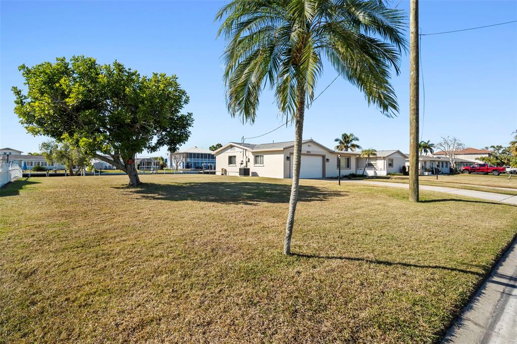 A grassy yard features a large tree, a palm tree, and a single-story house — 5003 COMMONWEALTH ROAD, PALMETTO, FL