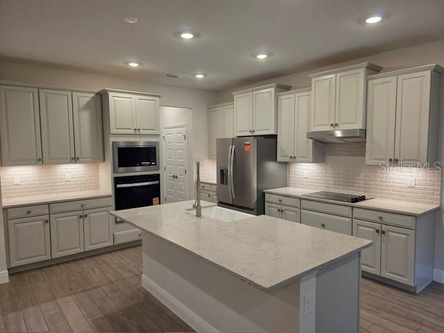 A kitchen island with a farmhouse sink and quartz countertop sits before a sliding glass door — 11827 SHINE VIEW LANE, WINTER GARDEN, FL