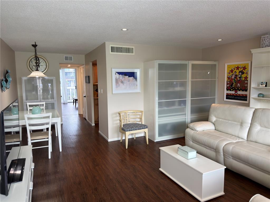 A living and dining area with dark wood floors, a white sofa, and a glass cabinet — 2650 PEARCE DRIVE UNIT 409, CLEARWATER, FL
