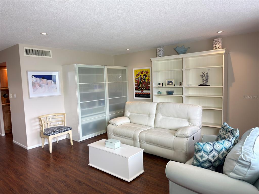 A living room features a white sofa, a coffee table, and a large white bookshelf — 2650 PEARCE DRIVE UNIT 409, CLEARWATER, FL