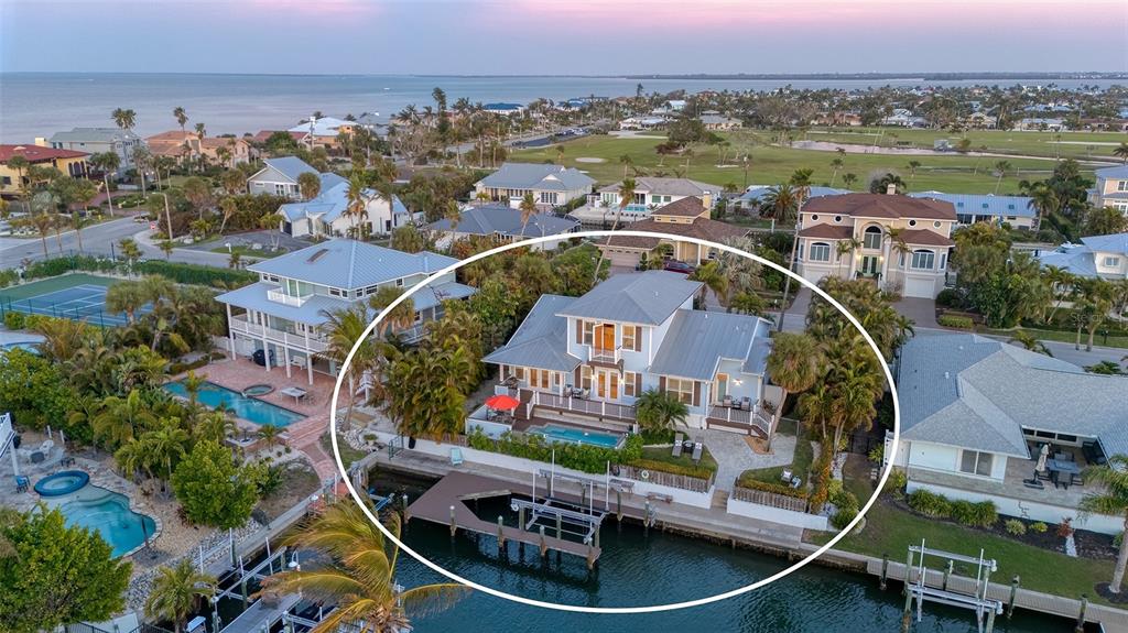 An aerial view of a waterfront house with a private dock, pool, and metal roof — 605 N POINT DRIVE, HOLMES BEACH, FL