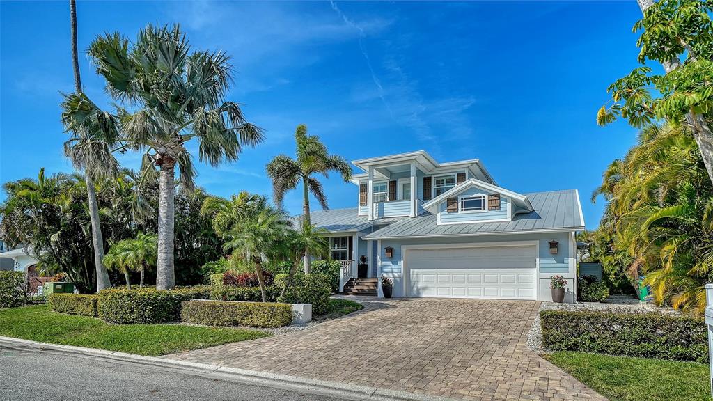 A two-story light blue house with a metal roof and a paved driveway — 605 N POINT DRIVE, HOLMES BEACH, FL
