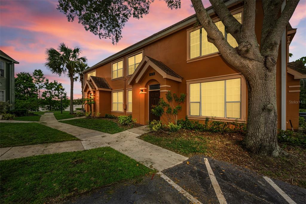 A two-story orange stucco building with a large tree and a paved parking lot — 9078 LAKE CHASE ISLAND WAY UNIT 9078, TAMPA, FL