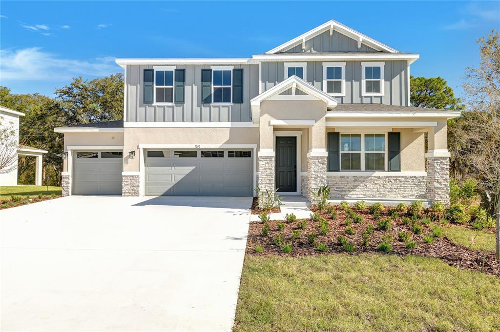 A two-story suburban house features a gray garage, stone accents, and a covered front porch — 1010 CLOUD RIDGE COURT, MOUNT DORA, FL