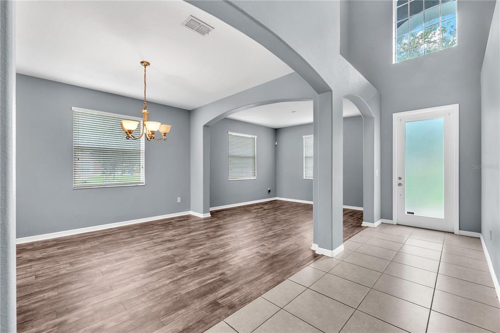 An entryway with tiled floors leads into a dining area featuring wood-look flooring and arches — 10626 LIBERTY BELL DRIVE, TAMPA, FL