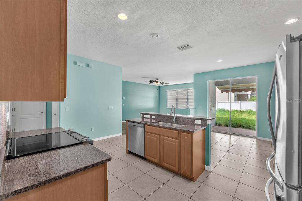 A kitchen with wood cabinets, granite countertops, stainless steel appliances, and light blue walls — 10626 LIBERTY BELL DRIVE, TAMPA, FL
