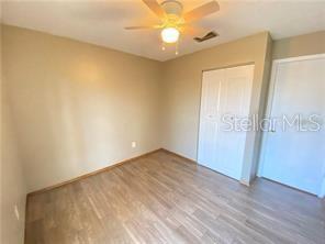 An empty bedroom with light wood-look flooring, beige walls, a ceiling fan, and two doors — 1409 MADRID WAY, WINTER SPRINGS, FL