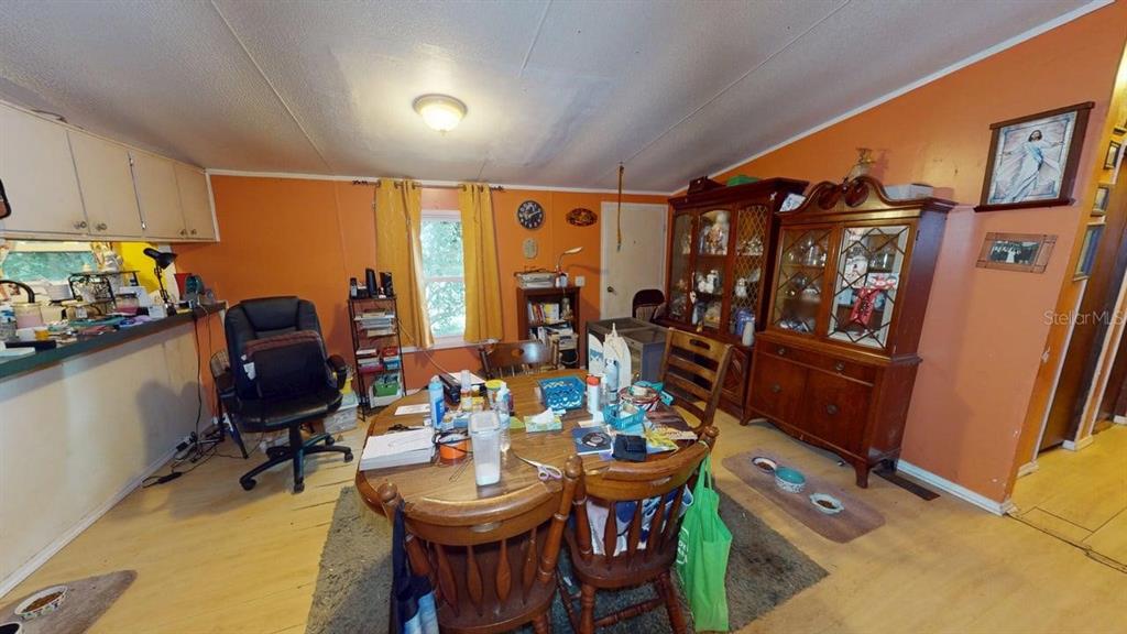A dining room with orange walls, a wooden table, and a large hutch — 30501 CLEARVIEW DRIVE, WESLEY CHAPEL, FL