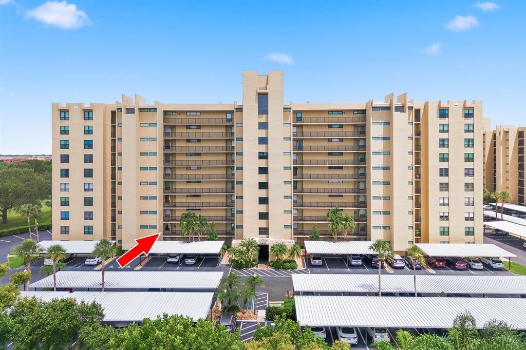 An exterior view of a multi-story apartment building with covered parking spaces in front — 2621 COVE CAY DRIVE UNIT 203, CLEARWATER, FL