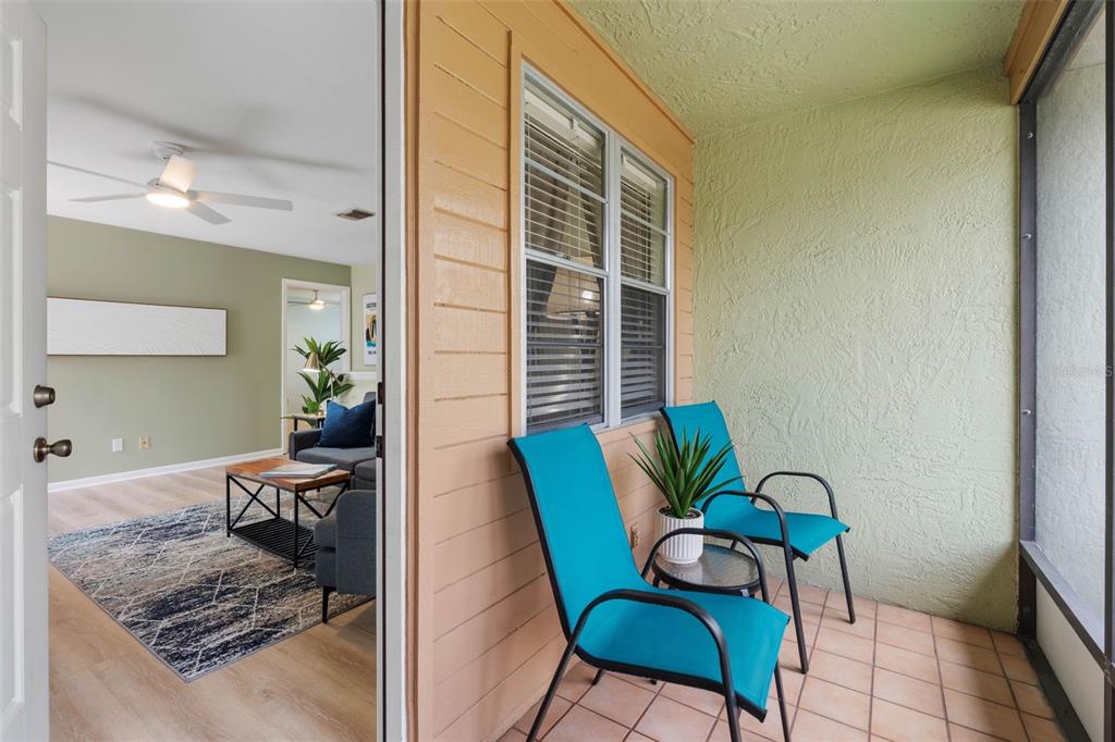 A view from a doorway looking out onto a screened balcony with two blue chairs — 2833 ORANGE TREE CIRCLE N UNIT A, PALM HARBOR, FL