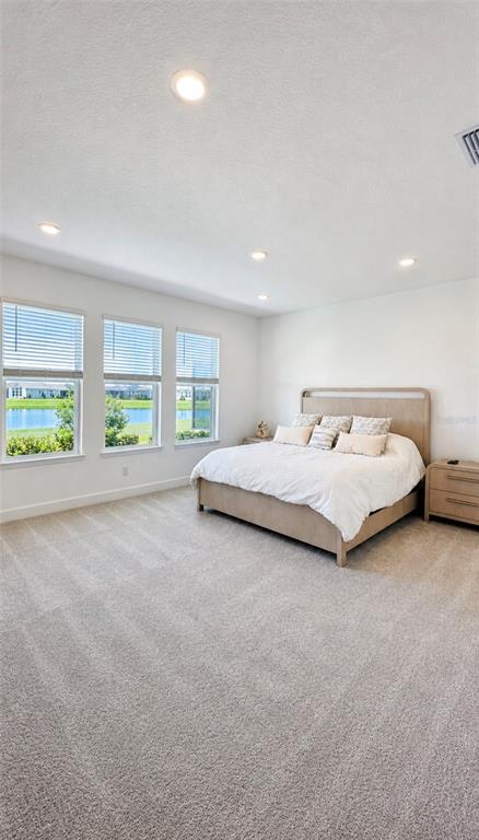 An open-concept kitchen with dark cabinets, a large island, and tile flooring faces a living area — 1854 LONGLINER LOOP, WESLEY CHAPEL, FL
