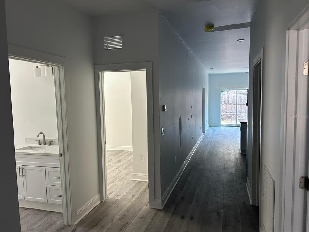 A hallway with light wood-look flooring leads to a sliding glass door at the end — 705 S ORANGE AVENUE, BARTOW, FL