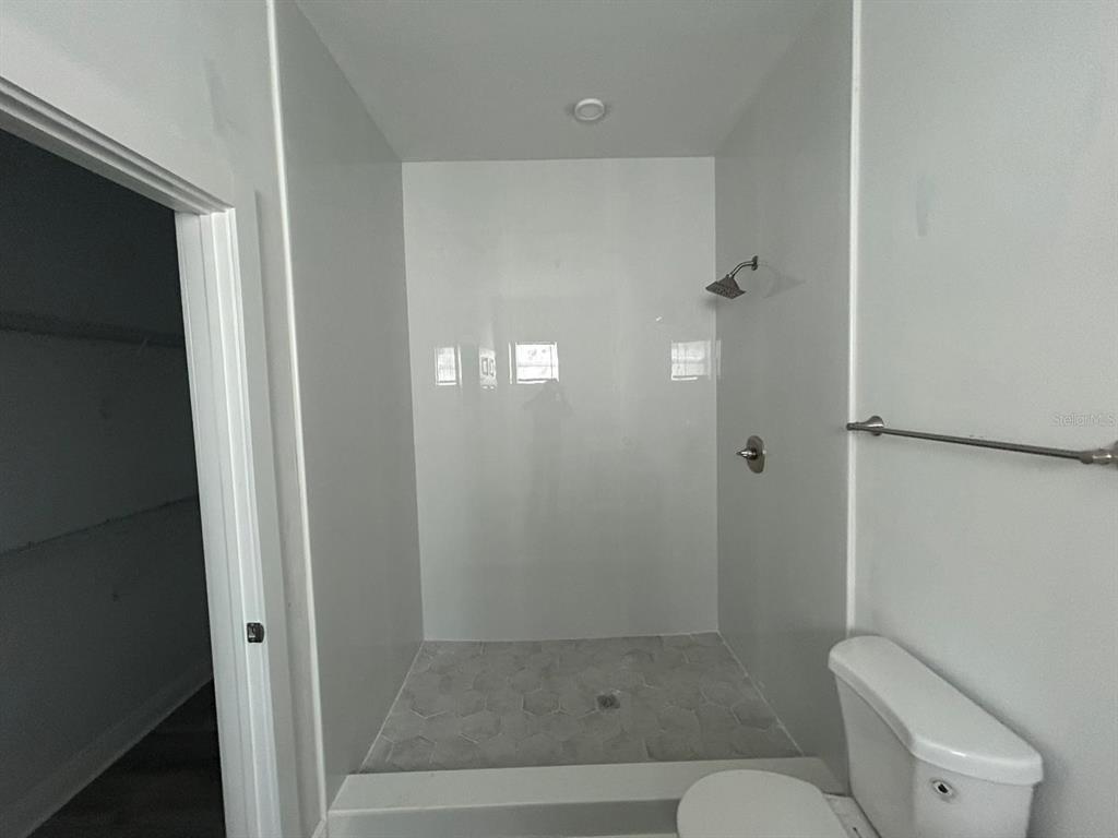 A bathroom features a walk-in shower with light-colored tile and a white toilet — 705 S ORANGE AVENUE, BARTOW, FL