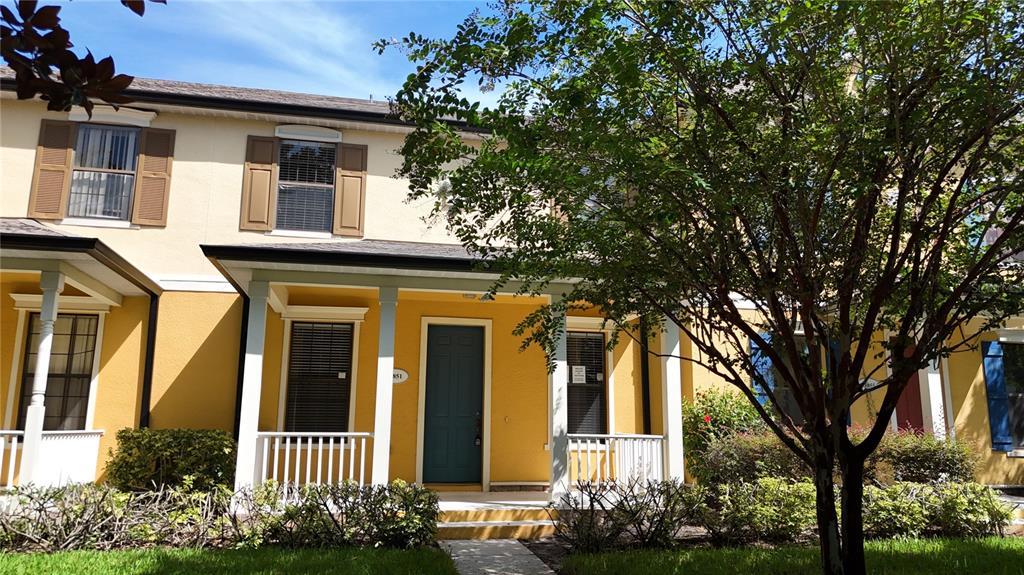 A two-story yellow townhouse features a covered front porch and a dark teal front door — 13851 BEAUREGARD PLACE, ORLANDO, FL